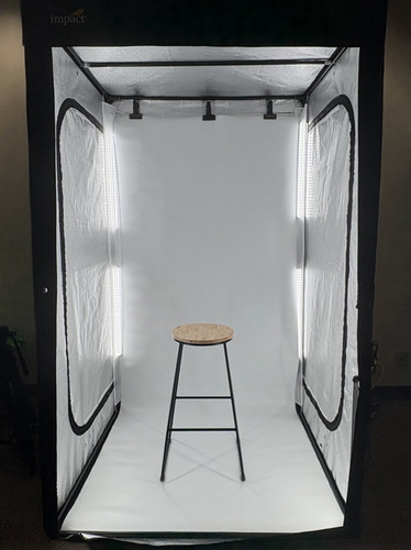 Studio photo setup featuring a white backdrop with a stool in the center, illuminated by soft lights on either side.